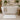 A large stone bath mat in a cream white placed in front of a freestanding chic bathtub in a modern, monochromatic bathroom.
