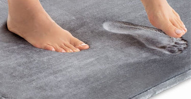 Memory foam bath mats with feet sinking into it.